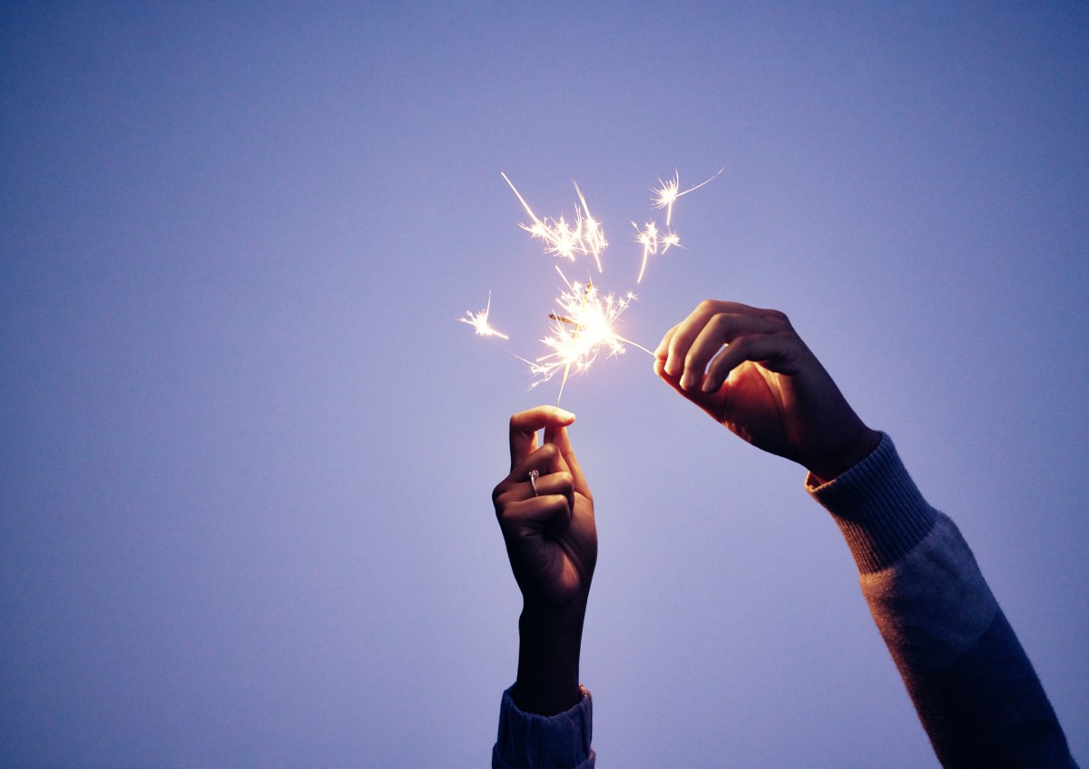 Sparkler, hand and person at night for new years eve celebration with bright, burning fun to celebrate. Celebrating, sparkle and blue nighttime background with a firework or firecracker in hands