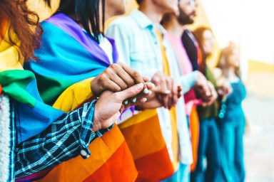 Group of lgbt people holding hands outside – Diverse happy friends hugging outdoors – Gay pride concept with crowd of guys and girls standing together on city street