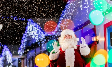 Santa Claus on village street at night, waving