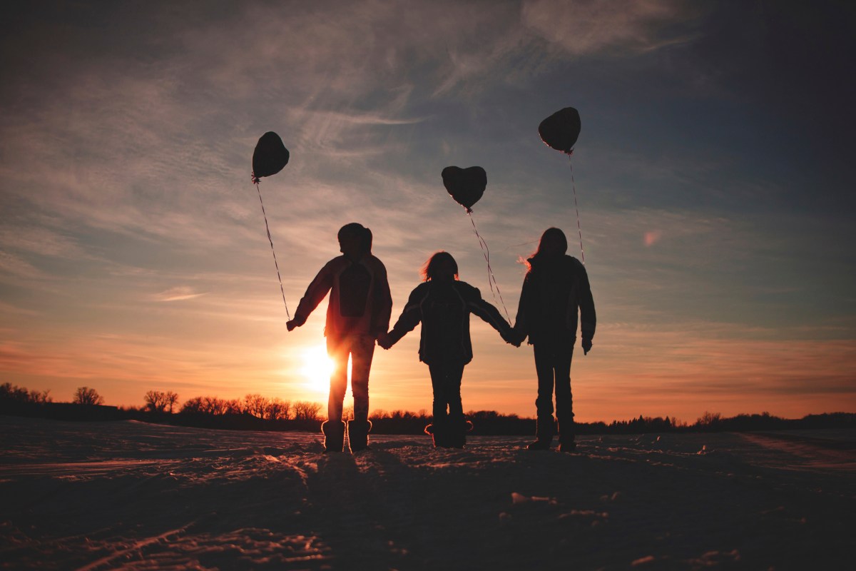 Caucasian girls walking with balloons at sunset